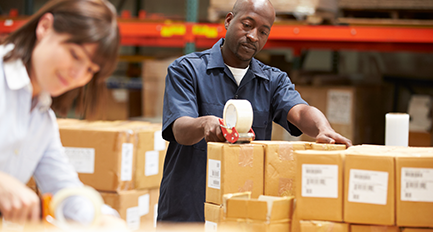 Employees packing boxes in a warehouse.