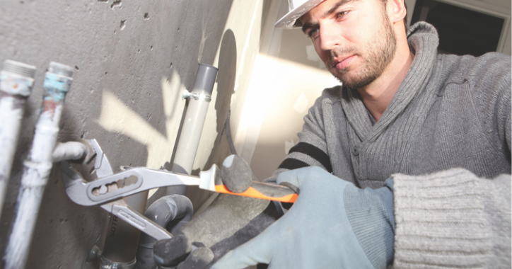 A man in a hard hat tightening a bolt.